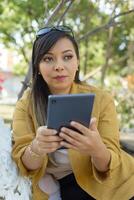 Woman sitting on a bench in a garden using her tablet. photo