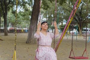 mujer balanceo en un al aire libre parque. foto