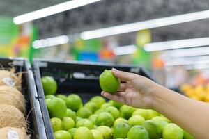 Hand holding a lemon in a supermarket. photo