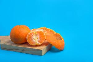 Mandarin with peel and another peeled on blue background. photo