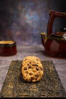 Vanilla chocolate chip cookies with tea set in the background on cement table. photo