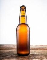 Cold beer bottle without label isolated on wooden table with white background. photo