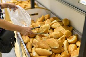persona seleccionando panes en un supermercado. un pan pararse. foto