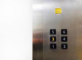 Group of Black Elevator push buttons with yellow bell, warning or alarm buttons on stainless steel background with copy space that shows passenger pressed on third floor for going up or down. photo