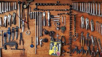 Many different sizes of tools, wrenches and pliers hanging on wooden panel background. Tool and object for fixing maintenance or repair car, machine or motorcycle concept photo