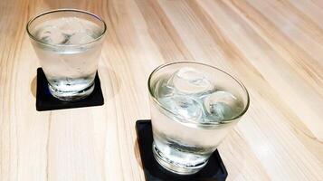 dos vaso de frío aguas en de madera mesa con Copiar espacio. refresco Bebiendo en madera antecedentes. foto