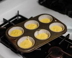 a tray of regular cornbread batter spooned into cupcake papers photo