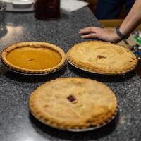 top down view of three pies just before they are sliced up for serving at a family gathering photo