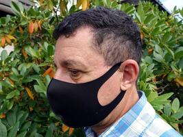 image depicting the face of a man with a black protective anti-contagion mask photo