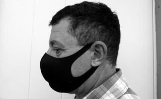 image that portrays the face of a man with a black protective anti-contagion mask photo