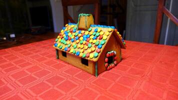 a home-made gingerbread house with the roof covered with chocolates photo