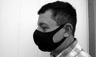 image that portrays the face of a man with a black protective anti-contagion mask photo