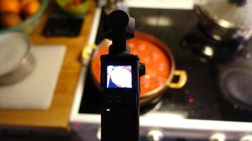 A digital camera is filming homemade meatballs simmering in tomato sauce photo