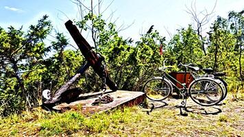 Digital painting style representing two bicycles parked near a large ancient anchor photo