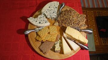 Mixed cow cheeses served on a wooden plate with slices of wholemeal bread photo