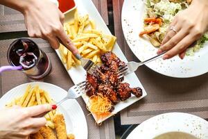 grupo de personas comiendo comida alrededor un mesa foto