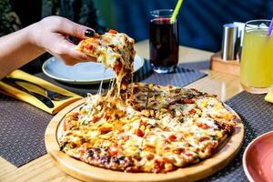 Person Taking a Slice of Pizza From a Table photo