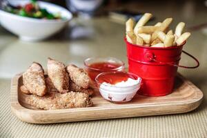 rojo Cubeta lleno con papas fritas siguiente a cuenco de inmersión salsa foto