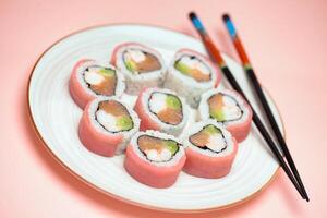 Sushi Plate With Chopsticks on Pink Background photo