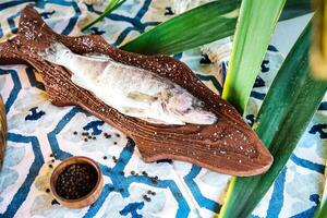 Fish Resting on Weathered Wooden Plank on a Table. photo