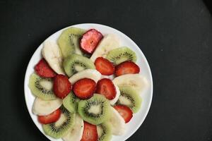 Freshly Sliced Kiwi and Strawberry Arrangement on a White Plate photo