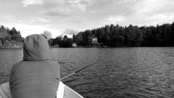 Black and white photo of a woman from behind, resting while fishing