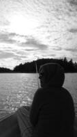 Black and white photo of a woman from behind, resting while fishing