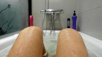 Legs and knees sticking out of the water and soap suds during a hot bath photo