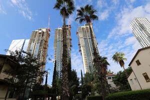 Tel Aviv Israel 03 28 2024. Buildings and structures in Tel Aviv through the foliage of tall trees. photo