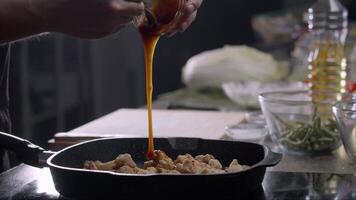 il capocuoco a il asiatico ristorante prepara generale tso pollo e Aggiunge un' dolce e acida salsa per un' padella con fritte pezzi di pollo. vicino su. lento movimento. 4k video