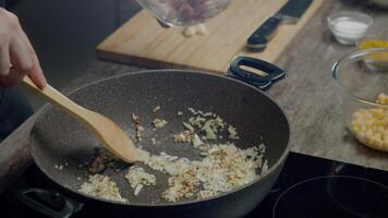 ein Mann Köche saftig gebraten Zwiebeln im ein braten schwenken und dann fügt hinzu gehackt Hähnchen Filets zu ihnen. schließen hoch. schleppend Bewegung. 4k video