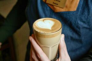 Person Holding Cup of Coffee With Heart Design photo