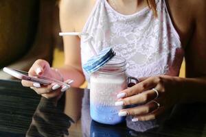 Woman Sitting at Table With Jar of Liquid and Cell Phone photo