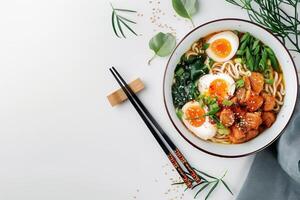 Asian ramen noodles on a white background. Egg noodles, eggs, meat, seaweed. There are ingredients scattered nearby, an empty space. photo