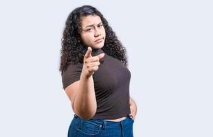 Serious young woman pointing at the camera, isolated. Young girl pointing at you frowning isolated photo