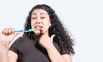 Young woman with gingivitis holding toothbrush isolated. Girl suffering from gum pain holding toothbrush. People holding toothbrush with gum problem photo