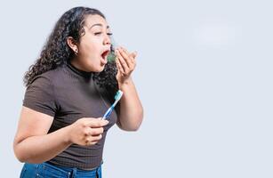 joven mujer participación cepillo con malo aliento aislado. persona con cepillo y malo aliento aislado, persona con halitosis foto