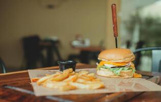 Delicious hamburger with french fries on a wooden table. Cheeseburger with french fries served on wooden table with copy space photo