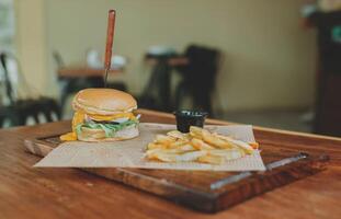 hamburguesa con queso con francés papas fritas servido en de madera mesa con Copiar espacio. delicioso hamburguesa con francés papas fritas en un de madera mesa foto