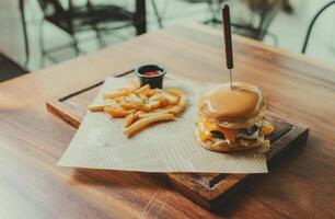 Appetizing burger with fries served on a wooden table. Traditional hamburger with fries served on a restaurant table photo