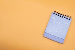 Blue desk calendar for SEPTEMBER 2024 isolated on orange background. Calendar concept with copy space. Flat lay. photo