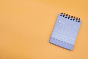 Blue desk calendar for OCTOBER 2024 isolated on orange background. Calendar concept with copy space. Flat lay. photo