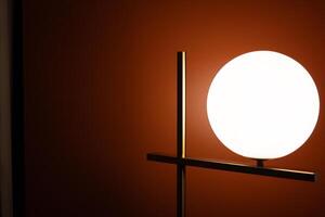 Round lamp, full moon shape with the light bulb inside shining on the wall background in the dark room with copy space. photo