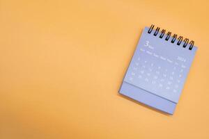 Blue desk calendar for MARCH 2024 isolated on orange background. Calendar concept with copy space. Flat lay. photo