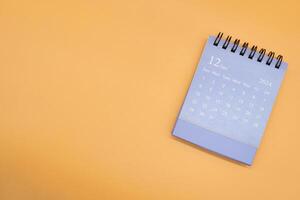 Blue desk calendar for DECEMBER 2024 isolated on orange background. Calendar concept with copy space. Flat lay. photo