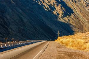 Desolate asphalt thoroughfare cuts through mountainous natural landscape photo