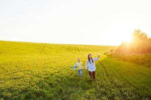 Cheerful and happy children play in the field and imagine themselves to be pilots on a sunny summer day. Kids dreams of flying and aviation. photo