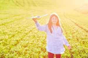 Sincere emotions. Happy little girl running on the field with yellow toy plane in their hands. photo