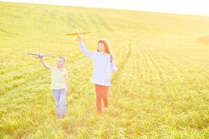 Cheerful and happy children play in the field and imagine themselves to be pilots on a sunny summer day. Kids dreams of flying and aviation. photo