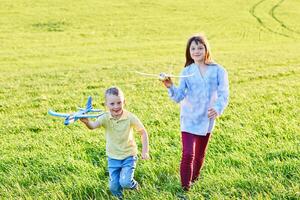 alegre y contento niños jugar en el campo y imagina sí mismos a ser pilotos en un soleado verano día. niños Sueños de volador y aviación. foto